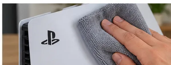 A hand wiping the white outer cover of a PS5 with a soft gray microfiber cloth.