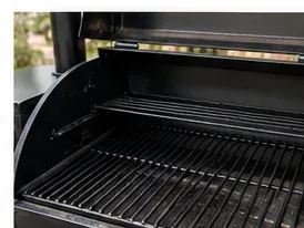 A clean open Traeger pellet grill with the heat-management components and black cooking grates reinstalled