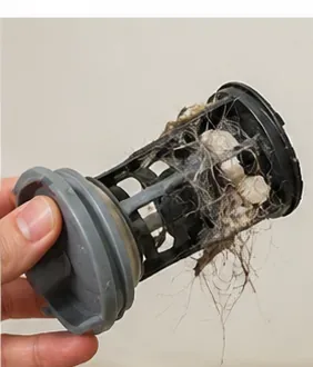 A removed washing-machine pump filter visibly clogged with lint, hair, and small debris