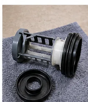 A clean washing-machine pump filter and sealing ring resting on a towel for inspection