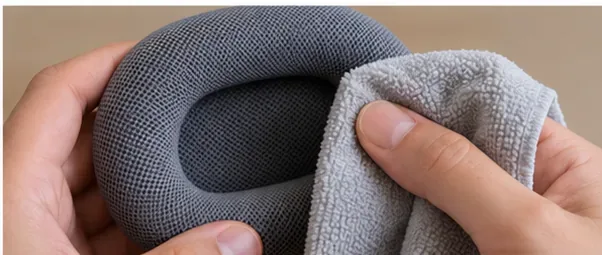 A separate soft cloth wiping the fabric surface of a removed AirPods Max cushion
