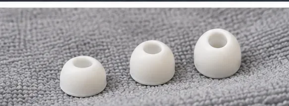 Three white AirPods Pro ear tips resting on a gray lint-free cloth