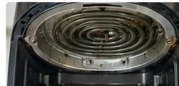 The removable basket is out, exposing the upper interior and accessible heating element of an air fryer.