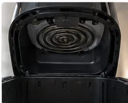 An open air fryer interior showing the heating coil and small food residue around the cooking chamber.