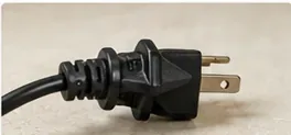An unplugged air fryer power plug resting on a kitchen counter before cleaning begins.