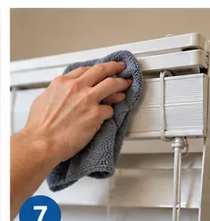 Hand wiping the headrail and cord area of horizontal blinds with a microfiber cloth