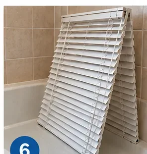 Clean horizontal blinds leaning in a bathtub to air-dry before reinstallation