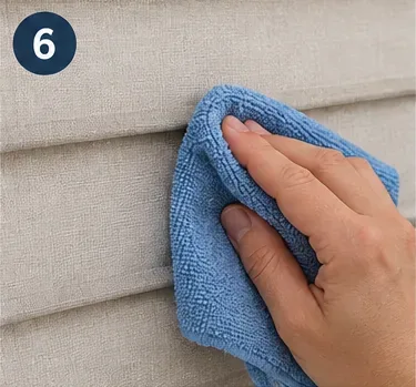 A clean blue microfiber cloth lightly blotting fabric blinds after spot cleaning
