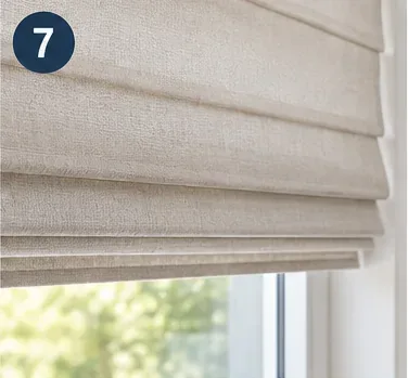 Clean beige fabric blinds lowered at a bright window while drying naturally