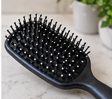 A clean black paddle hairbrush resting on a countertop after washing and drying