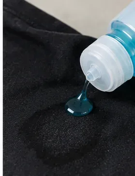 A small amount of blue liquid laundry detergent being applied directly to an underarm area of a black shirt
