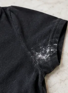 Close-up of chalky white deodorant residue concentrated along the underarm seam of a black T-shirt