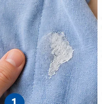 Close-up of a dried white fabric-glue patch on a light blue garment