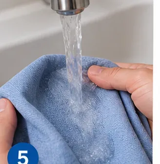 Blue garment being rinsed under clean running water at a sink