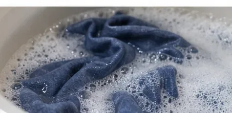 A blue garment soaking in sudsy wash water.