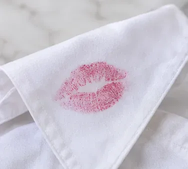 A white shirt collar with a fresh pink lipstick mark before cleaning begins.