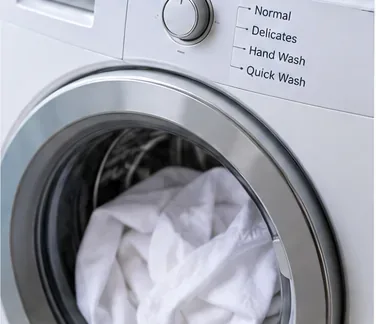 A white washable garment being loaded into a front-loading washing machine.