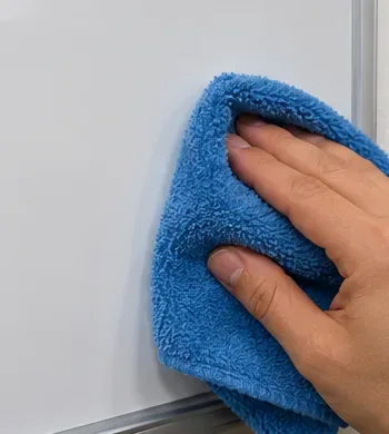 A blue microfiber cloth drying the lower edge of a clean dry-erase board