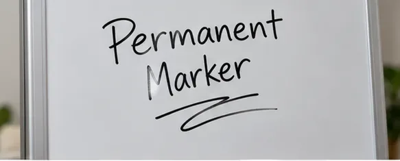 Black permanent-marker writing on a framed white dry-erase board before cleaning