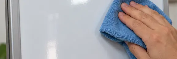 A clean blue microfiber cloth making another pass across a mostly clean dry-erase board