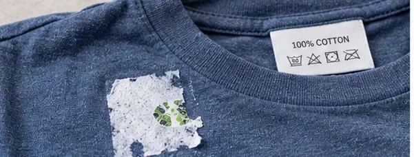 Blue cotton shirt with sticker paper and adhesive residue near a visible care label