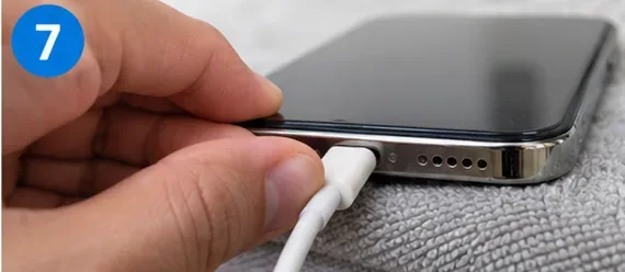 A charging cable being connected to a smartphone after the drying period.