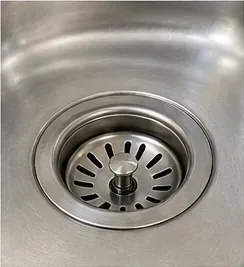 Stainless-steel kitchen sink with a standard removable basket strainer in the drain opening