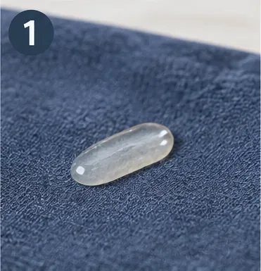 A cooled clear bead of hot glue resting on blue woven fabric