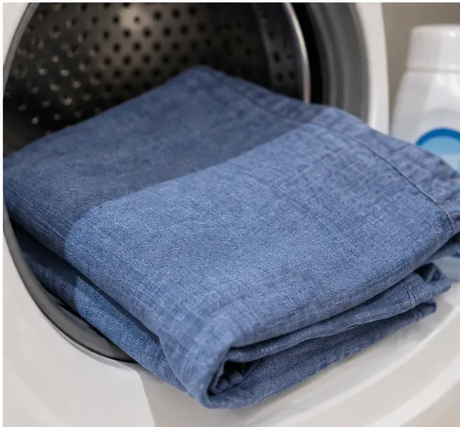 A blue garment placed at the opening of a washing machine after nail-glue pretreatment