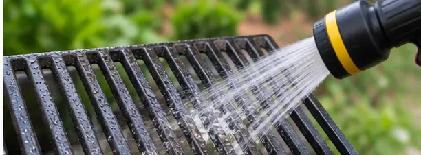 Cast iron grill grates being rinsed with clean water outdoors