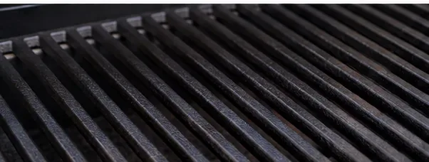 Dark cast iron grill grates resting after a seasoning heat cycle