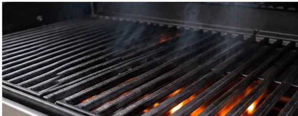 Cast iron grill grates heating over a gas grill flame with the lid open
