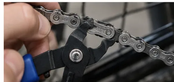 Master-link pliers squeezing a bicycle quick link on the lower run of the chain