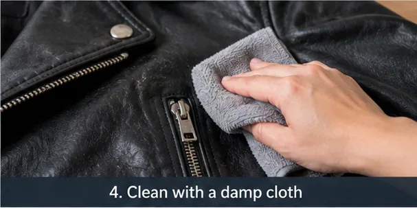 A gray microfiber cloth wiping a small section of a black leather jacket with light pressure.