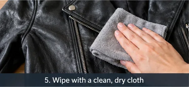 A clean gray cloth being pressed gently against a black leather jacket to remove surface moisture.