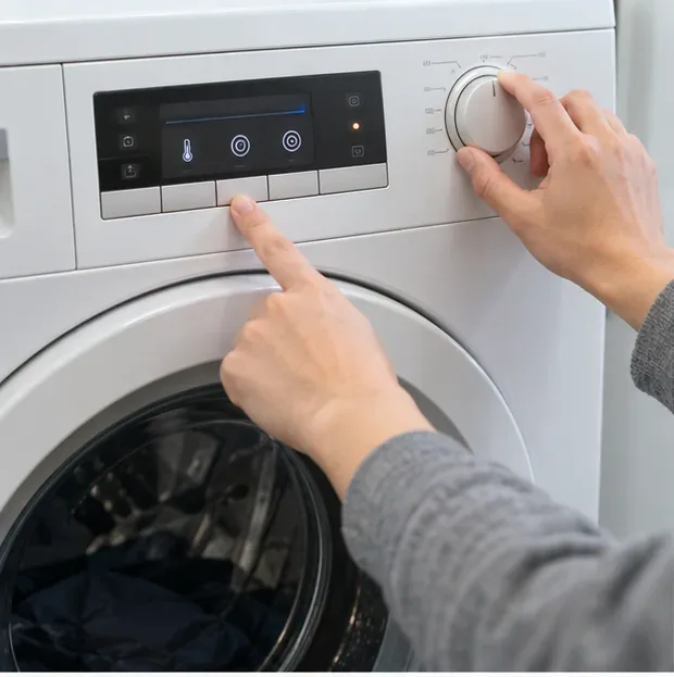 Hands adjusting a washing-machine control panel for an additional rinse or spin cycle.