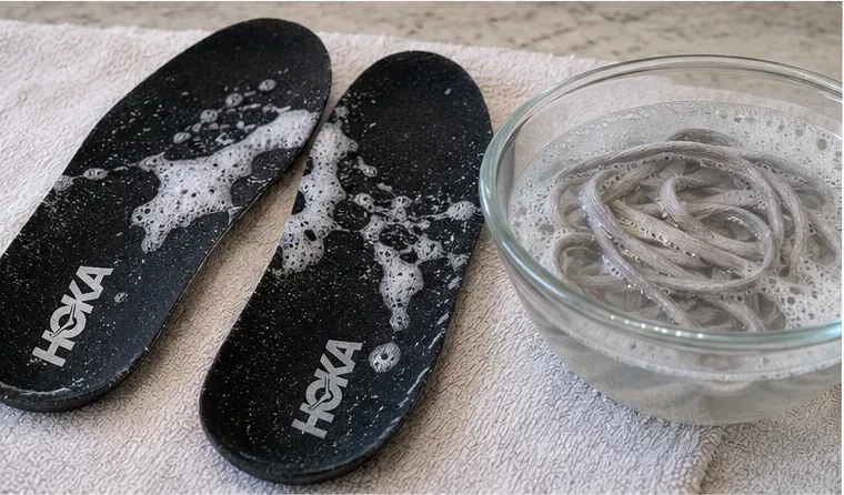 HOKA insoles on a towel beside shoelaces soaking in a bowl of mild soapy water