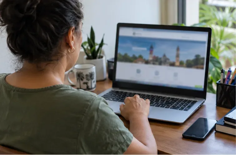 Moradora consulta um portal municipal em um notebook para iniciar a emissão da segunda via do IPTU