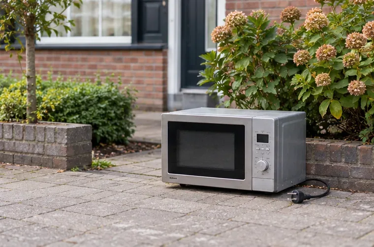 Een complete magnetron staat op een eigen betegelde oprit, naast een voortuin en buiten de openbare looproute.