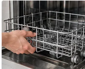 Main tirant le panier inférieur d’un lave-vaisselle pour accéder au fond de la cuve