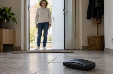 Een bewoner staat op afstand in een deuropening en kijkt naar een powerbank op de vloer.