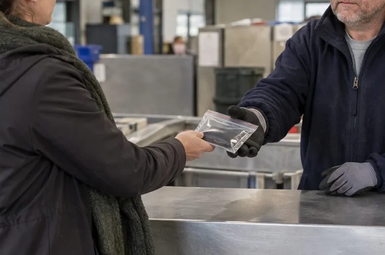 Een medewerker achter een neutrale inzamelbalie neemt een afzonderlijk verpakte accu aan