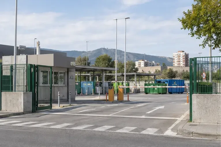 Entrada de un punto limpio metropolitano con contenedores separados y acceso señalizado