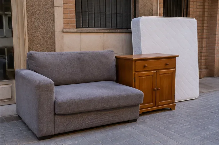 Sofá, pequeño mueble de madera y colchón colocados juntos antes de su retirada