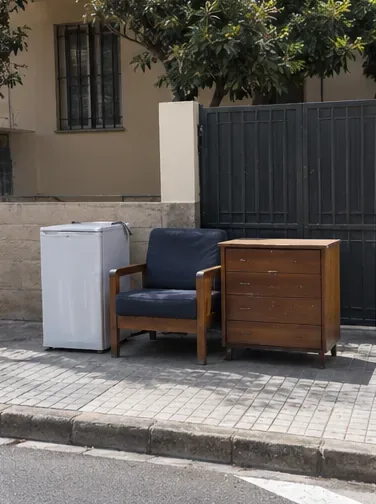 Sillón, cómoda y pequeño electrodoméstico agrupados junto al bordillo dejando libre la zona principal de paso