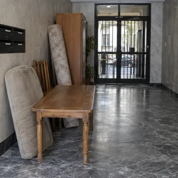 Mesa, colchón y piezas de madera agrupados dentro del portal junto a una ruta de acceso despejada