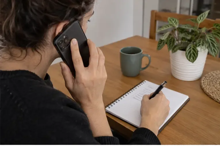 Una residente llama por teléfono y anota en un cuaderno la dirección, los objetos y el número de autorización