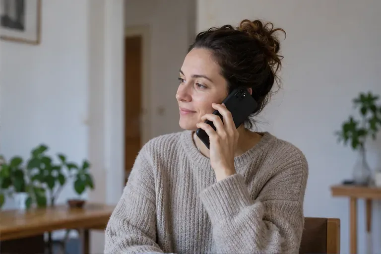 Una mujer llama por teléfono desde su vivienda para organizar la recogida de un mueble voluminoso.