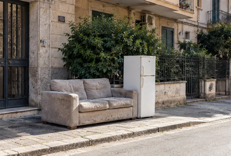 Un divano e un frigorifero sono collocati sul marciapiede davanti a un edificio in attesa del ritiro concordato