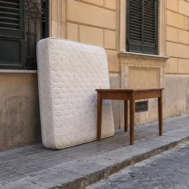 Un materasso e un tavolo di legno collocati sul marciapiede davanti a un edificio